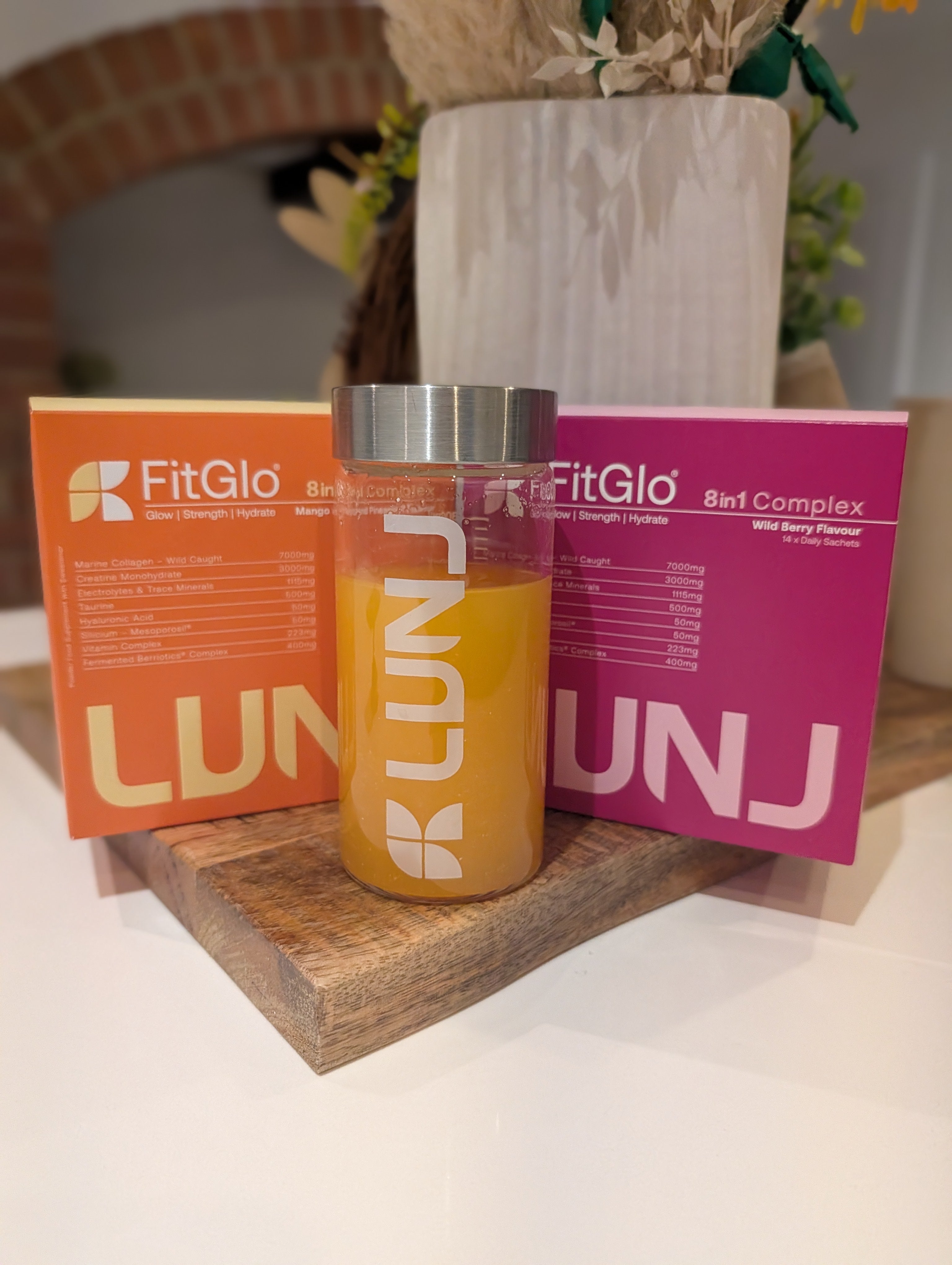 Delighted customer showing her LUNJ FitGlo boxes in Mango & Pineapple and Wild Berry flavours with bottle.